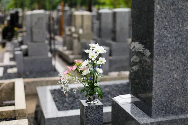 Bouquet de fleurs fraîches posé au pied d'une stèle dans un cimetière.