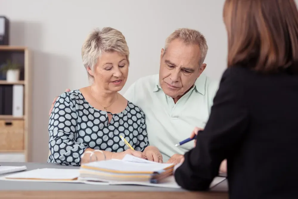 Couple senior accompagnant un conseiller pour la signature d'un contrat d'obsèques.
